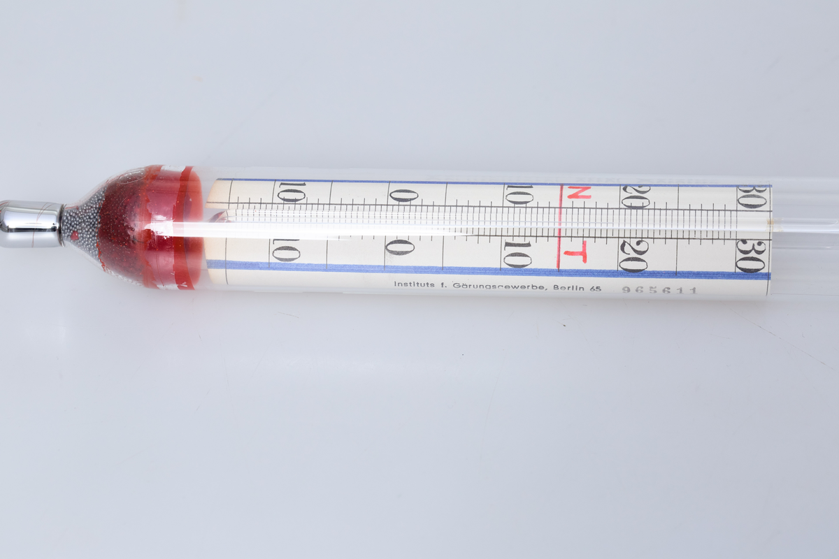 Alkometer eller spritmåler i glass, brukt til å måle alkoholstyrken i brennevin ved Toten Brenneri A/L.

Instrumentet består av en kort, tykk glasskropp med en rødfarget vekt i bunnen, og et langt, tynt målerør som stikker opp. På det tynne røret er det en måleskala som viser 80 til 100 vol% alkohol, basert på Gay-Lussac-skalaen (volumprosent). 

På den nederste delen av instrumentet er det en tilleggsskala med tall fra 10 til 0 til 30, samt merkene "N" og "T". Denne brukes sammen med et innebygd Celsius-termometer for å korrigere avlesningen etter væskens temperatur. Instrumentet er kalibrert for bruk ved 15°C 

Ligger i original papp hylse merket: 80-100 vol %, TOTEN BRENNERI A/L og NR 965611



Alkoholmeter med termometer
spritmåler med gradestokk
måle alkoholmengde i væske