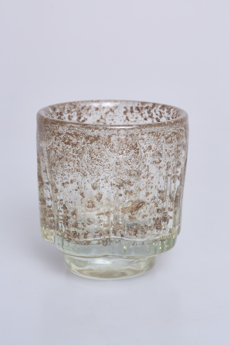 Vase eller lyslykt i lysgrålig, rillete glass med metallspon. Designet av Benny Motzfeldt for Randsfjord Glassverk. Etikettmerket på undersiden.