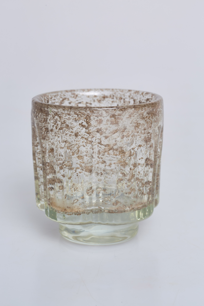 Vase eller lyslykt i lysgrålig, rillete glass med metallspon. Designet av Benny Motzfeldt for Randsfjord Glassverk. Etikettmerket på undersiden.