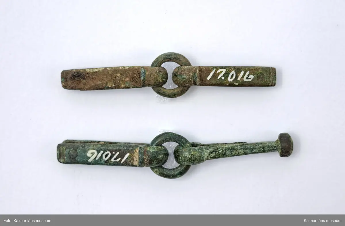 KLM 17016. Rembeslag, 2 st. Av brons. Ledade med ring i mitten.