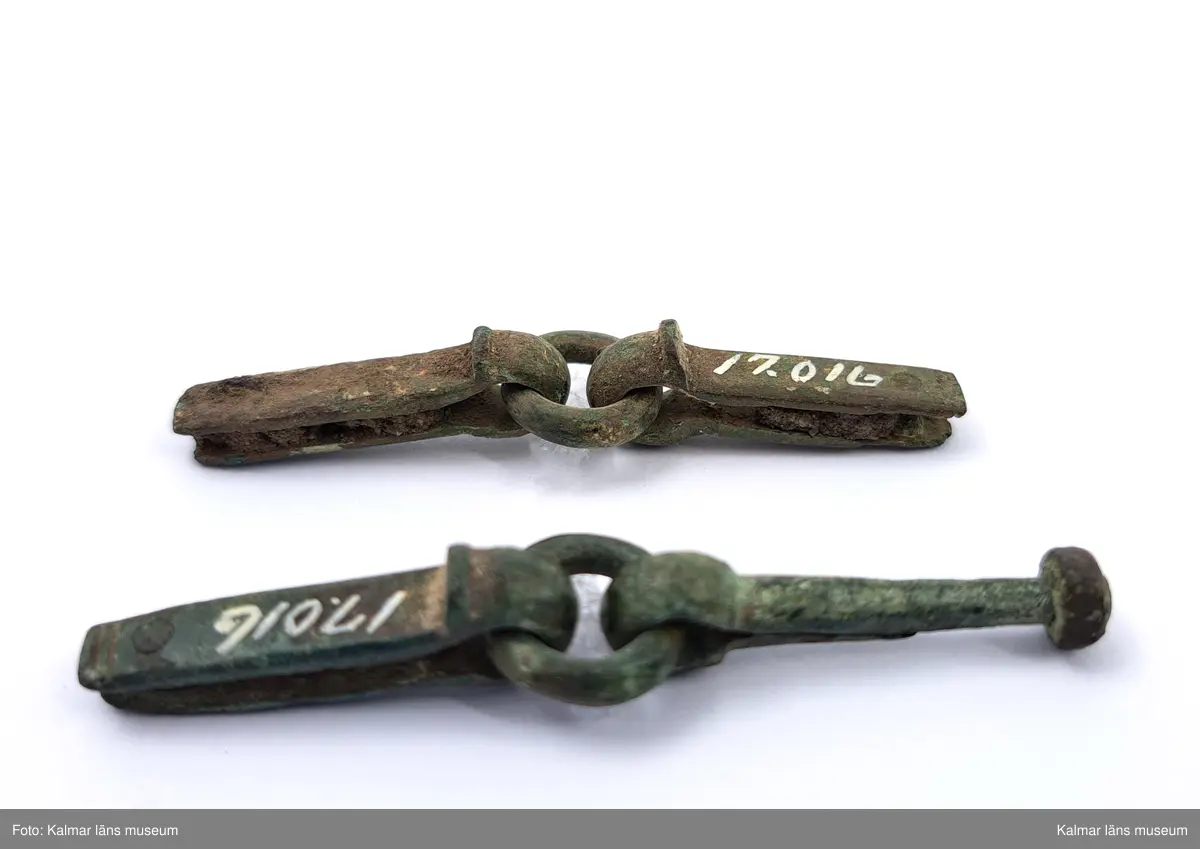 KLM 17016. Rembeslag, 2 st. Av brons. Ledade med ring i mitten.