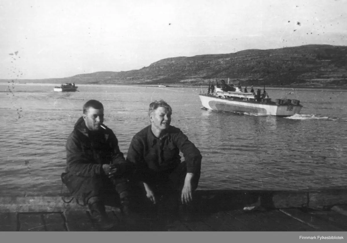To sovjetiske (ex. amerikanske) motortorpedobåter på vei ut fra Pummanki på Fiskerhalvøya. Begge fartøyene er av typen "Higgins 78 ft pt boat" (US NAVY betegnelse), som så er overført til den Sovjetiske marine under Lend/Lease avtalen. To marinesoldater tar seg en hvil på kaikanten.