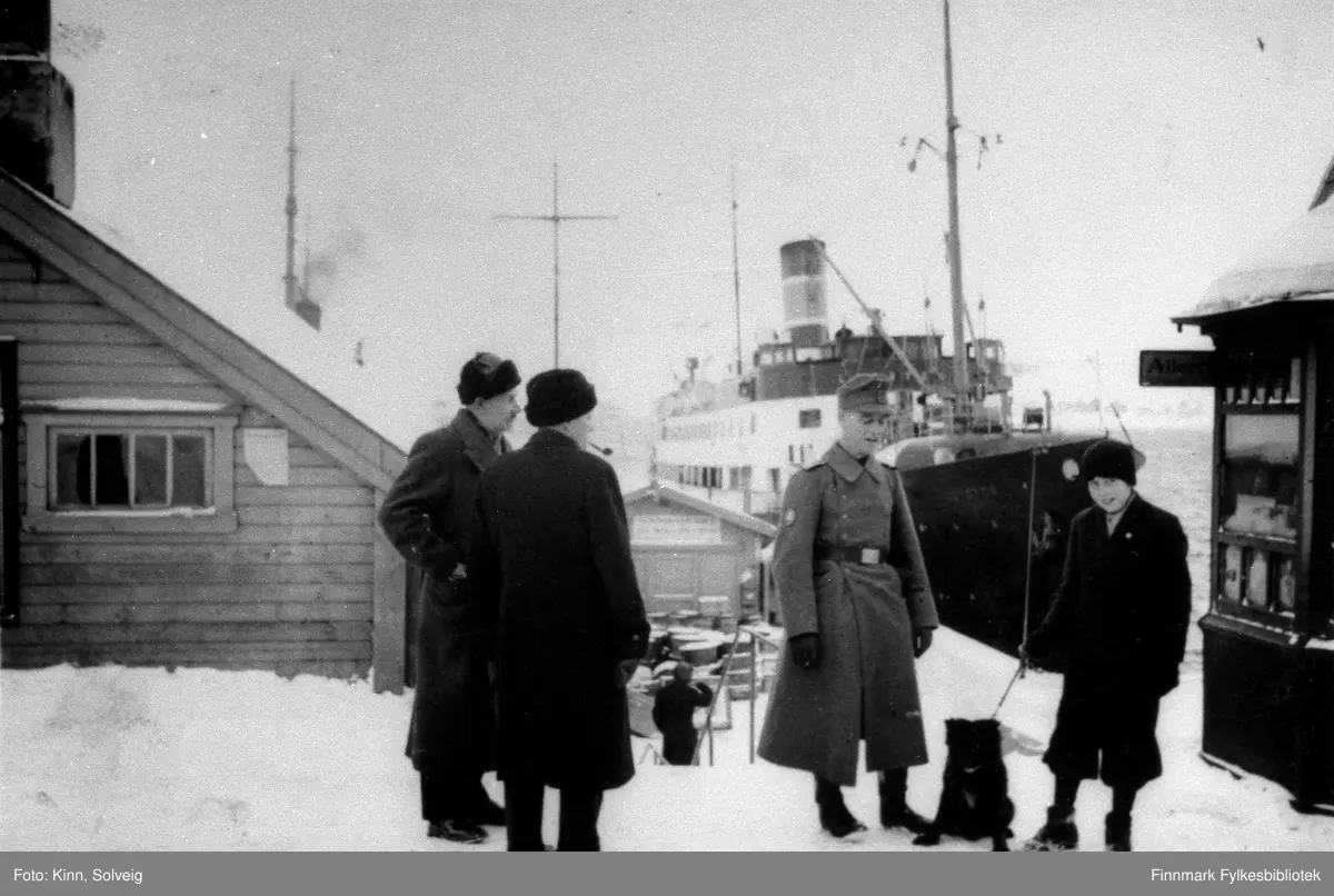 Tysk soldat sammen med to sivile menn og en sivil kvinne med hund på dampskipkaia i Hammerfest.