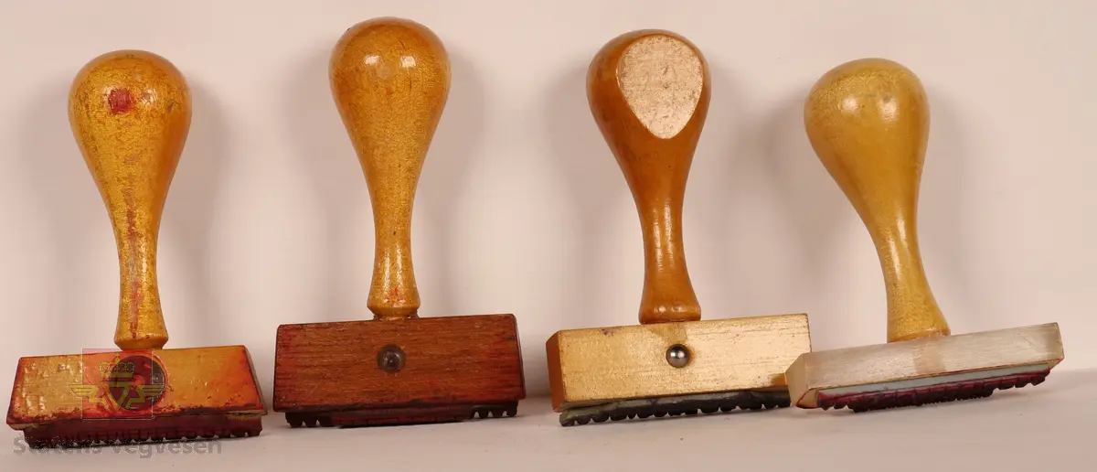 4 Stempler laget av tre som er lakkert. Lyse brun farge. Rektangulære i varierte størrelser med avlangt håndtak. Stempelplatene har fargene blå, rød, rød-brun og grå. Det ene stemplet har overdel som er gjennomsiktig med tekst som viser hva det skal stå på stempelplaten.