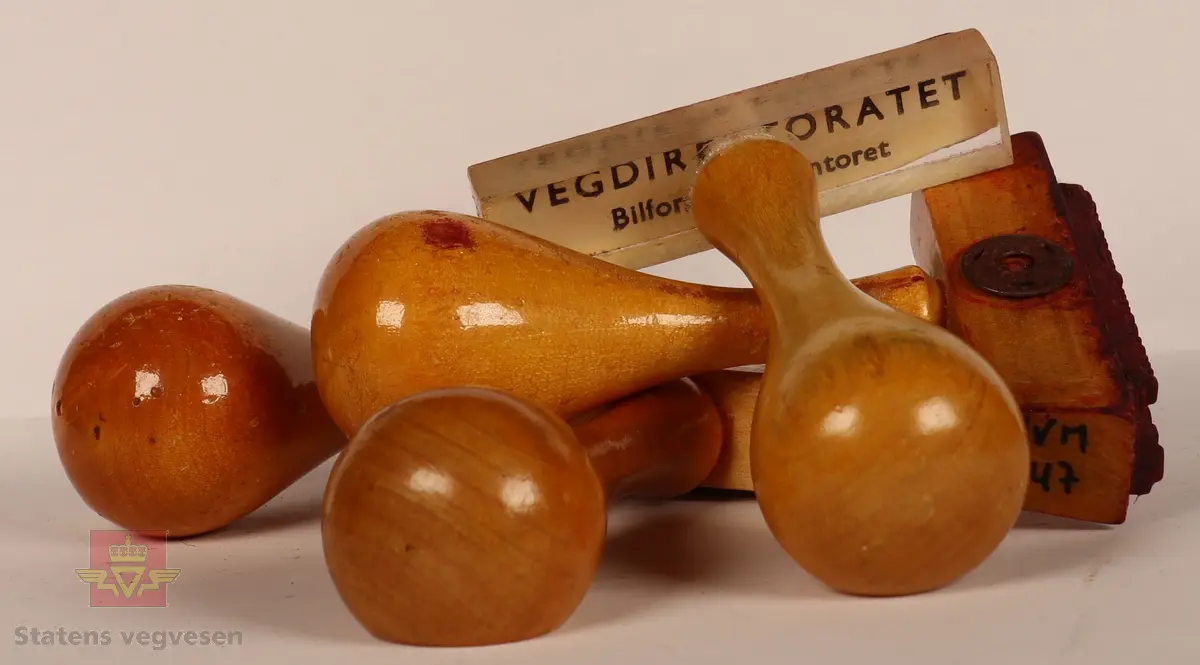 4 Stempler laget av tre som er lakkert. Lyse brun farge. Rektangulære i varierte størrelser med avlangt håndtak. Stempelplatene har fargene blå, rød, rød-brun og grå. Det ene stemplet har overdel som er gjennomsiktig med tekst som viser hva det skal stå på stempelplaten.