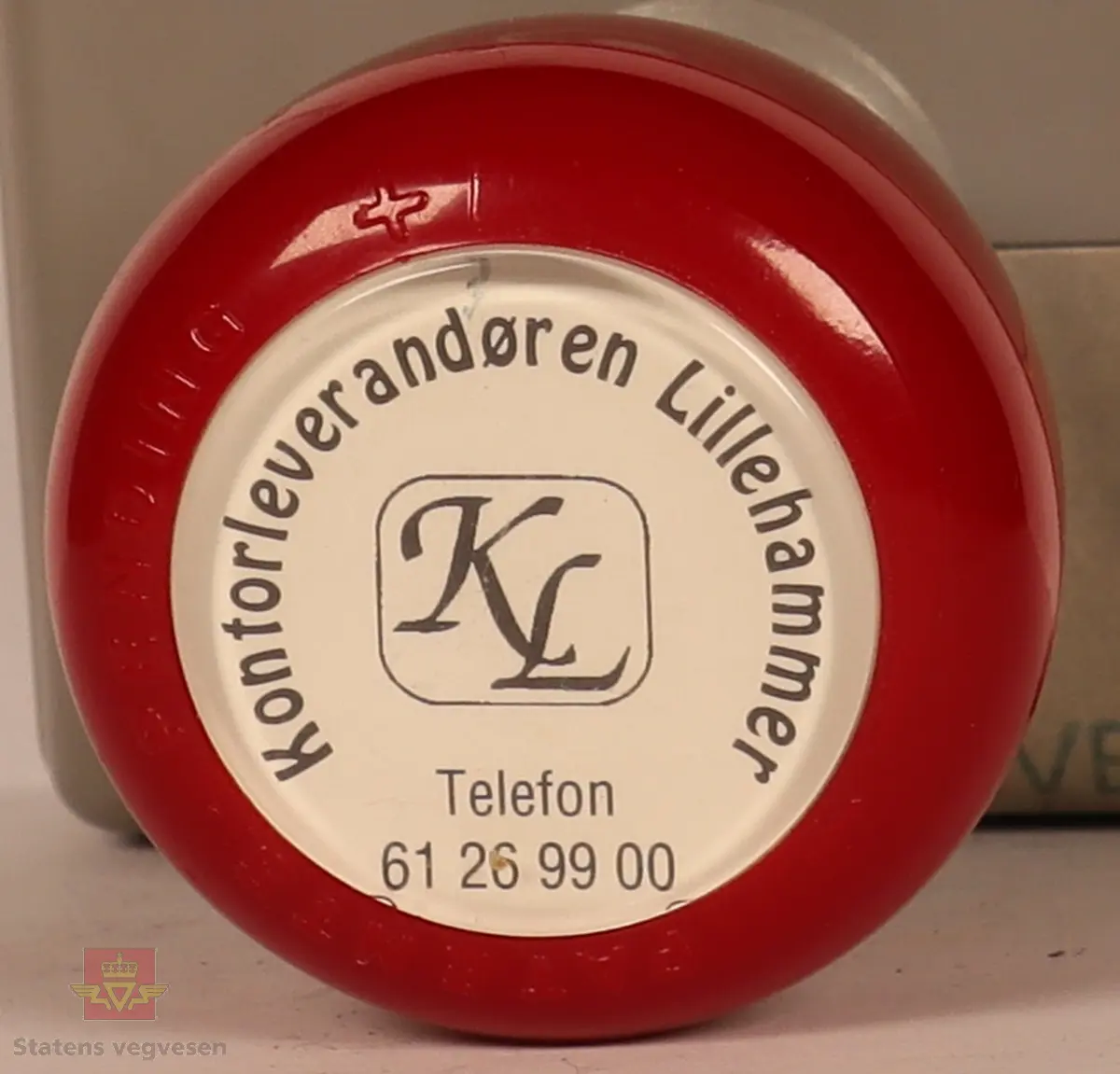 Rødt, grått, hvitt og svart stempel i plast. Firkantet med rundt håndtak. Stempel puten er tørket og har vegvesenets logo med tekst. 
