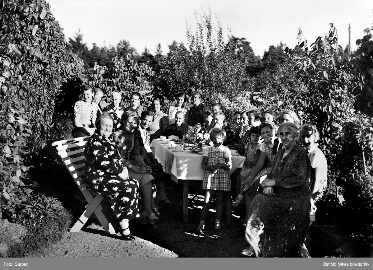 Kolonihagen til Borregaard på Opsund i Sarpsborg. Festlig lag ute i hagen, men samling rundt dekka bord, alle kvinner og barn er ukjente.