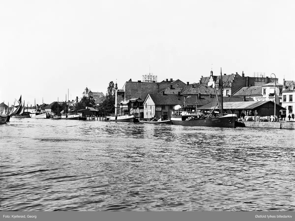Dampskipsbrygga i Fredrikstad, med båten Trafik 3 ved kai, flere dampbåter ligger til venstre for den. i bakgrunnen forsamlingshuset Valhalla bygd 1870, avholdslosje. 

Dampskipsbrygga med et stort skur som må ha blitt brukt til å plassere varer som skulle lastes/losses fra dampbåtene som la til her. Fisketorvet lå helt til venstre i fotoet - der vi ser båter med seil.