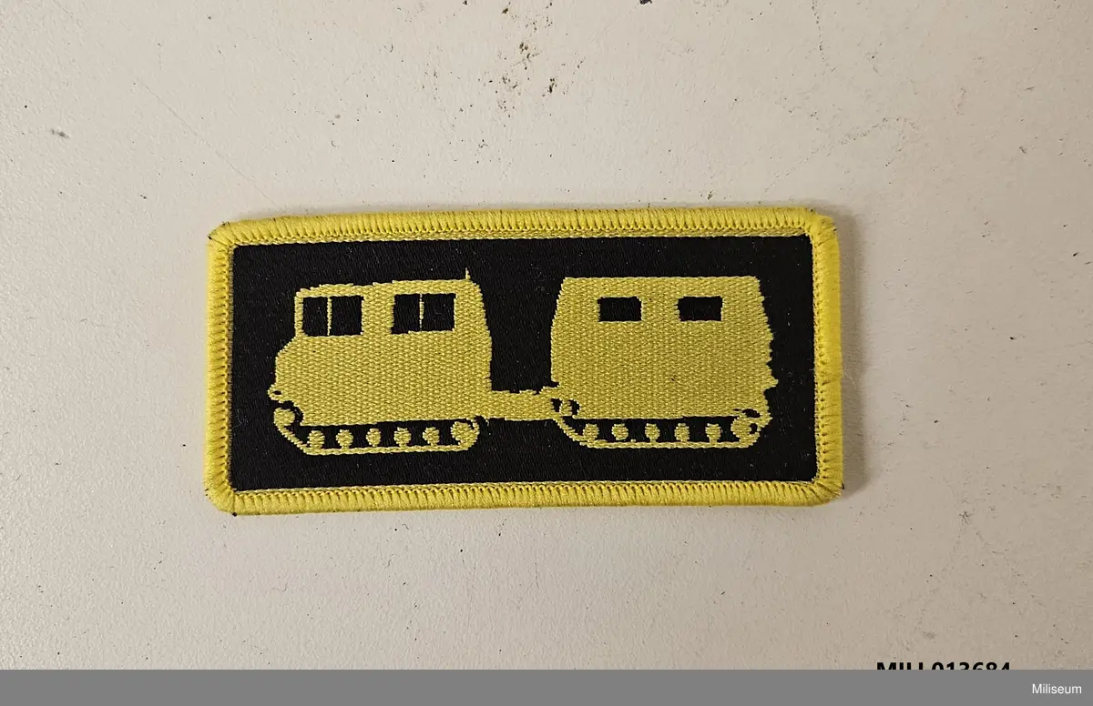 Utbildningstecken av textil med vävt motiv. Avsett att sys fast på högra uniformsärmen. Avser godkänd förarutbildning för bandvagn 206.