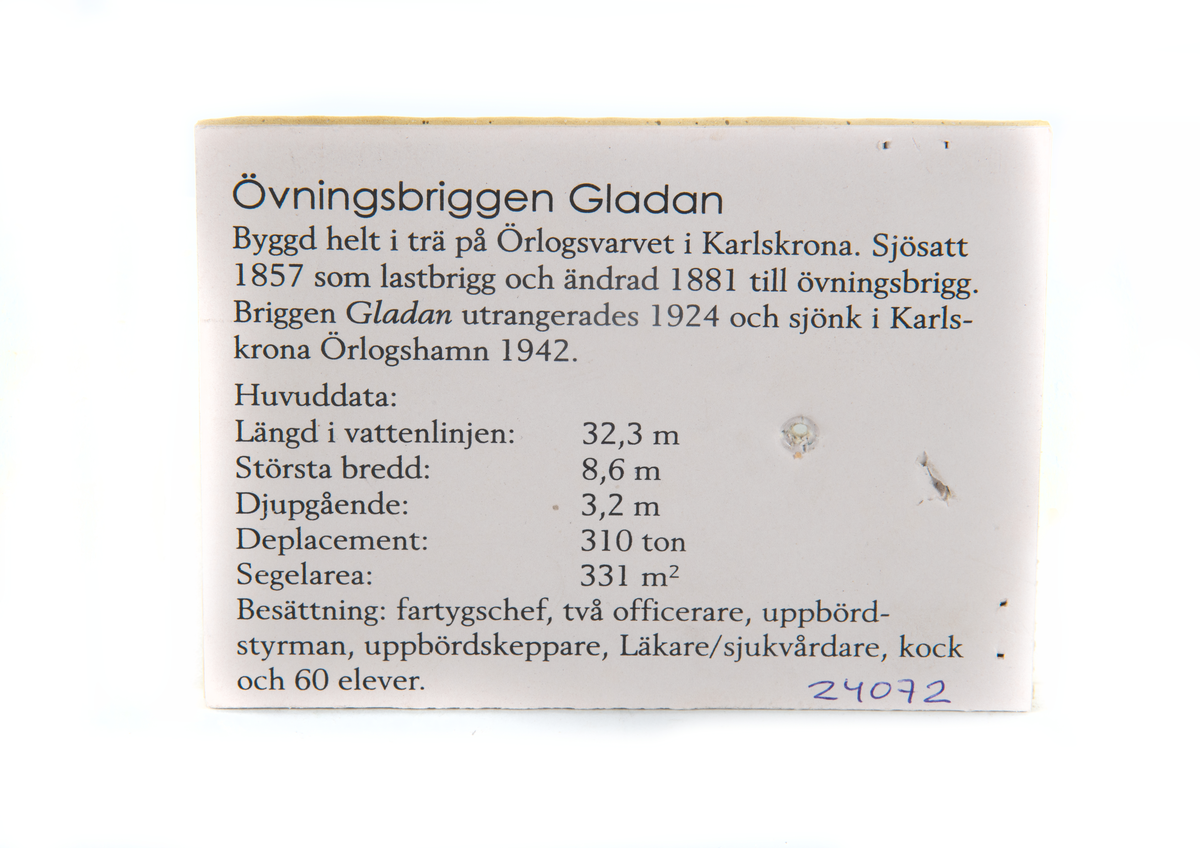 Fartygsmodell av Briggen GLADAN till ankars med beslagna segel. Utriggade waterbommar. En livbåt förtöjd vid varje bom, en livbåt förtöjd akter. Monterad på glasplatta.