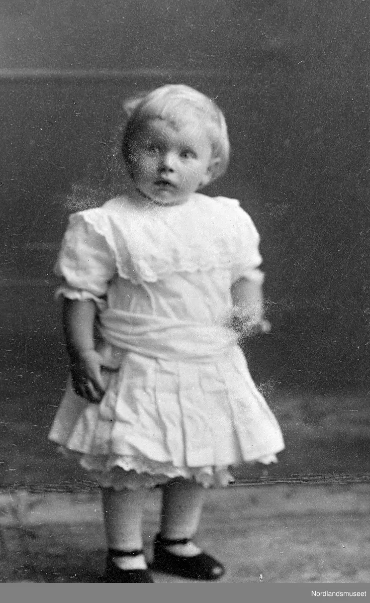 Portrett av en liten jente, stående.