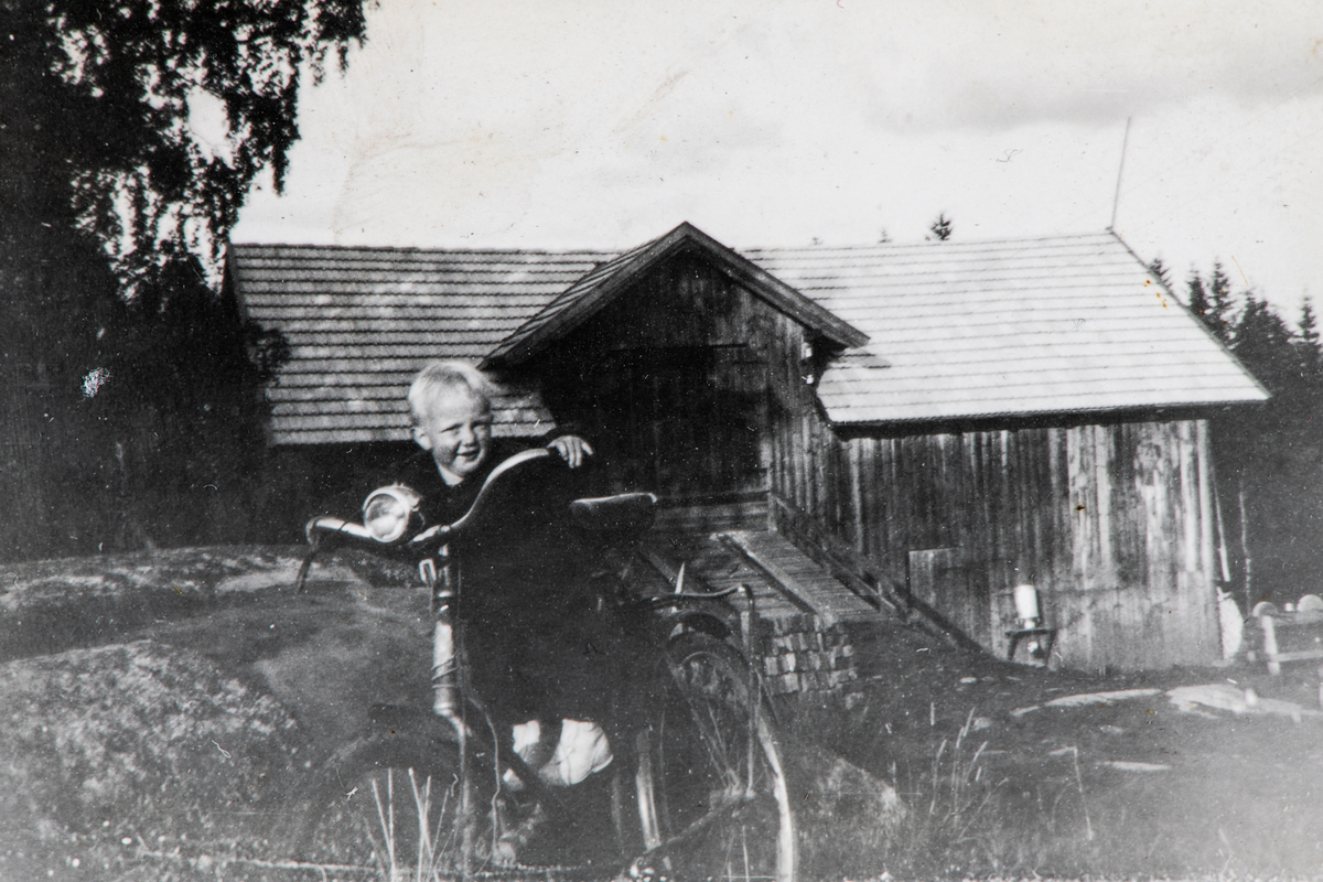 Liten gutt på sykkel for voksne,  foran låvebrua. Arne Hermann Gundersen på naboeiendommen Arneberget foran den gamle låven.