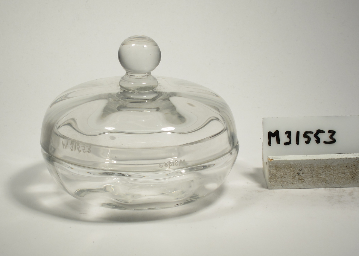 Burk och lock, båda närmast klotsegmentformade. Vertikal optik. Klotformad knapp.