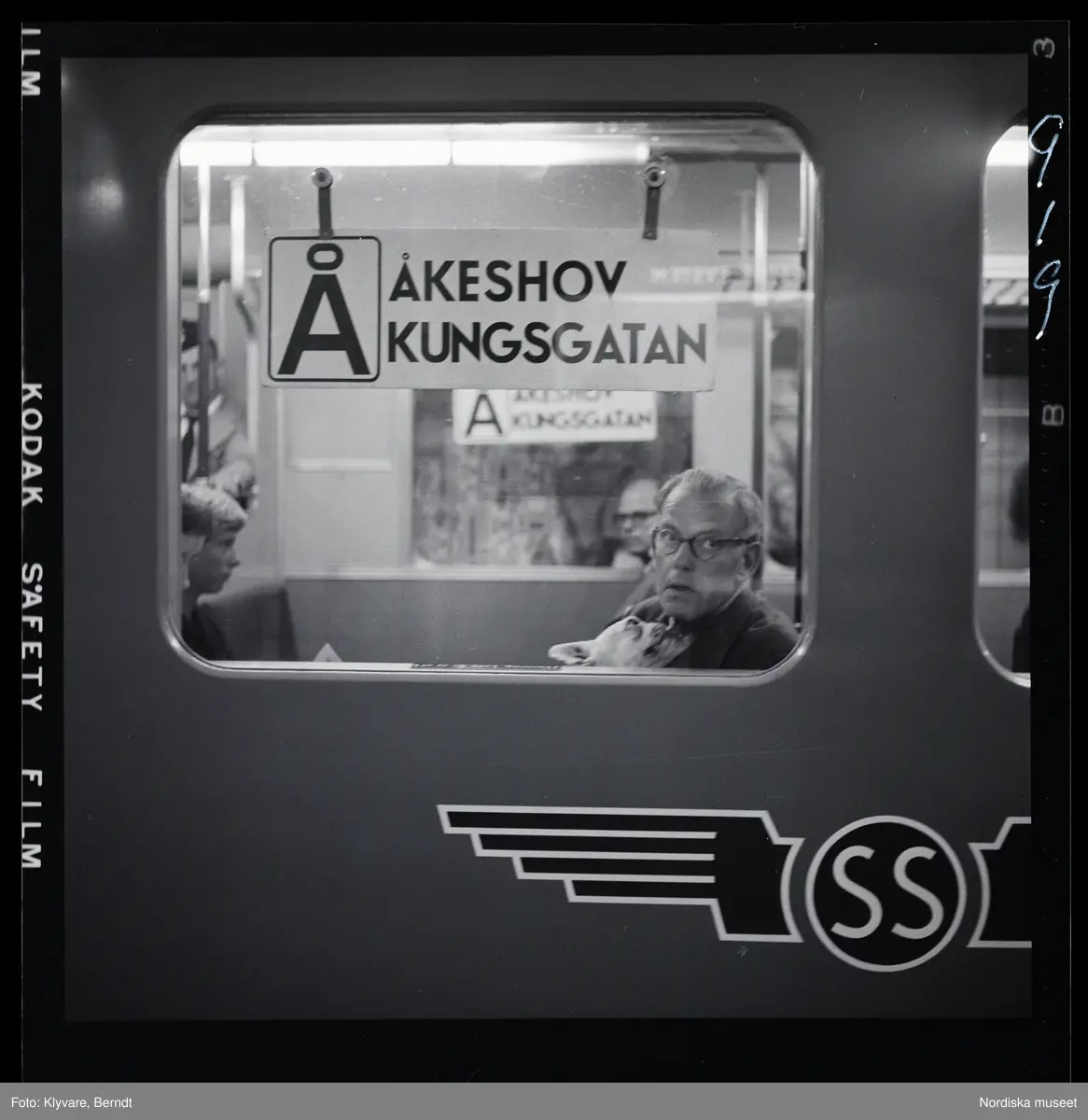 Stockholms tunnelbana. På linjen Åkeshov - Kungsgatan sitter en man i tågfönstret med en hund i famnen.