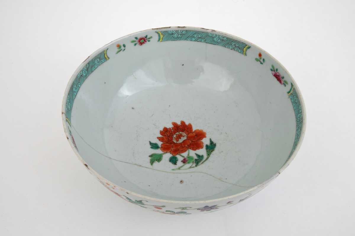 Bolle med fotring av porselen. Dekket med gråhvit glasur med polykrom blomsterdekor malt over glasuren. Dekoren delvis forgyllet.