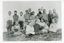 Skolebarn på Strand skoleinternat. To elever holder det norske flagget, tre andre holde buketter i hendene.