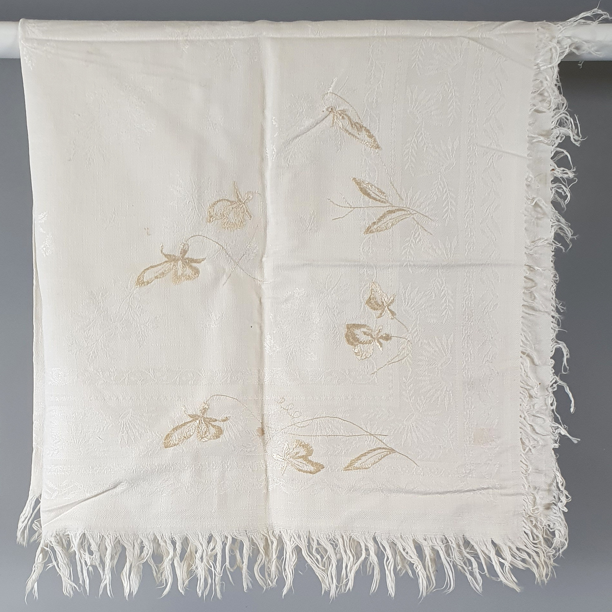 Duk av bomull med innvevd bmlomstermønster. Broderte blomster brodert med beige garn.