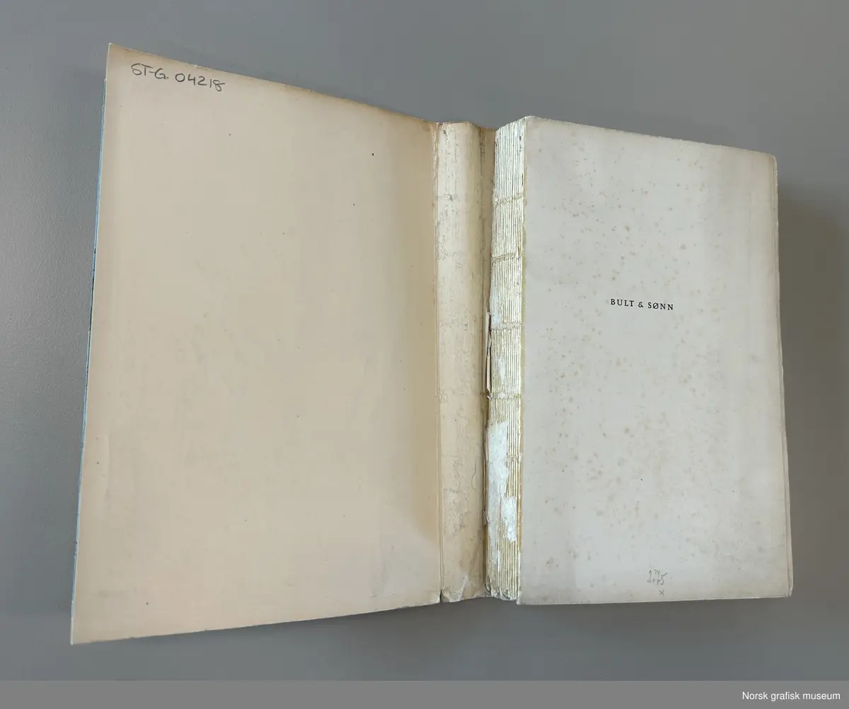 Bok med myk perm med tittelen "Bult & sønn. En Gøteborgroman" av Harry Hjørne. Utgitt i Oslo i 1946. Omslaget er blått med en illustrasjon i sort med gule detaljer. 
Boken har mykt pappomslag som er limt på. Dette har løsnet fra bokblokken.  