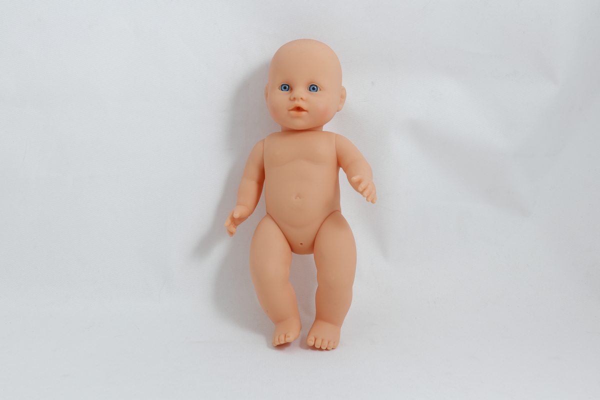 Babydukke, uten klær. Det er skrevet "Kristine" med tusj nederst på ryggen på dukka. 