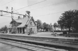 Väröbacka järnvägsstation med människor framför stationsbyggnaden och cyklar parkerade vid en stolpe.
