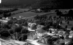 Flygbild över Landeryd järnväg och järnvägsstation nere till vänster och omgivande bebyggelse. I bakgrunden mot skogen ligger Landeryds kyrka och däremellan ses odlingslandskap. Här fanns till en början endast en hållplats utmed Halmstad-Nässjö Järnvägar, invigd 1877, men fick ett provisoriskt stationshus 1881 och 1886 uppfördes ett permanent. Detta byggdes om 1906 och är sedan 2018 ett statligt byggnadsminne.