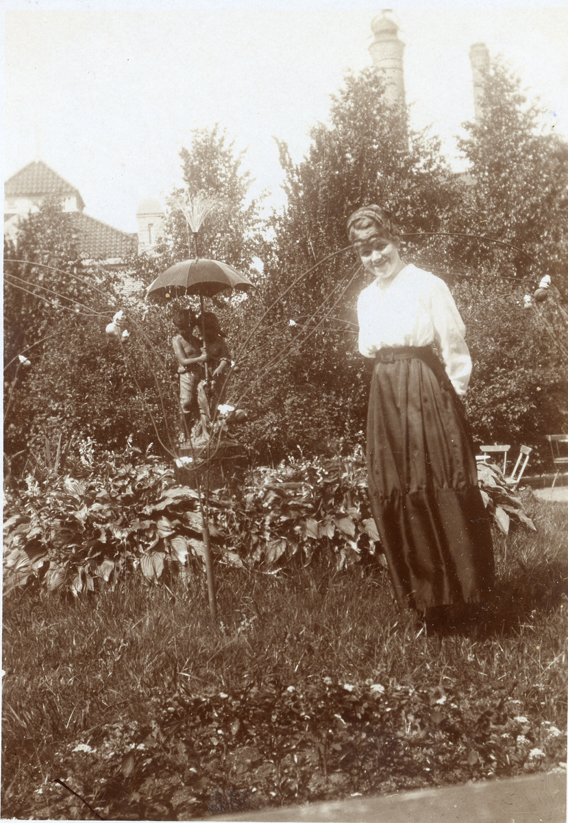 Foto av en flicka från Karlstad som står bredvid en staty (enligt text skriven i albumet).