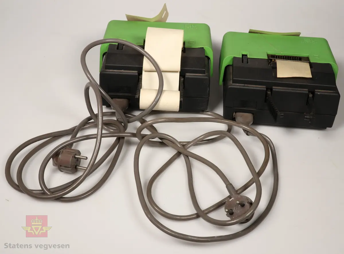 Elektriske regnemaskiner i grønn og svart farge. Grønt tastatur med svart tekst. Grå ledning. 
NVM 00106 (Har papirrull)
og
NVM 00106 - 001 (Mangler papirrull)
