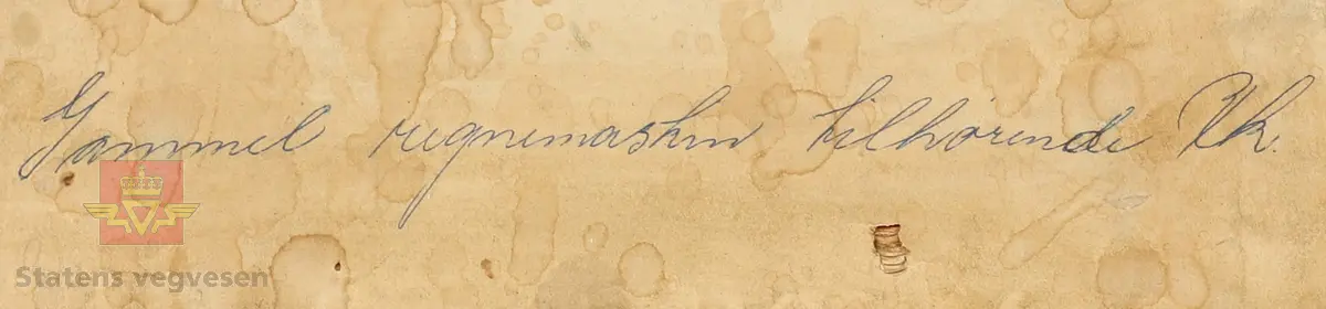 Mekanisk regnemaskin laget av metall som har et sveivehåndtak. Regnemaskinen sitter i en tre kasse med messinglås og trehåndtak. Regnemaskinen er gullfarget og svart, og er dekorert med logo. Sveivehåndtaker er sølv og brun farget og laget av tre. Inne i kisten henger en lapp. Det ligger også en liten nøkkel i kisten som hører til låsen. 