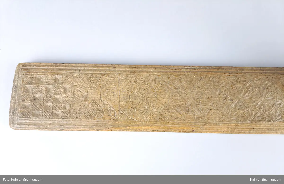 KLM 8325. Mangelbräde. Tillverkat av bok. Platt med kälade kanter. Ytan rikt ornerad med karvsnitt, cirklar, blommor, hjärtan m.m. Snidat handtag i form av en häst, något skadat. Inskrift: Anno 1786.