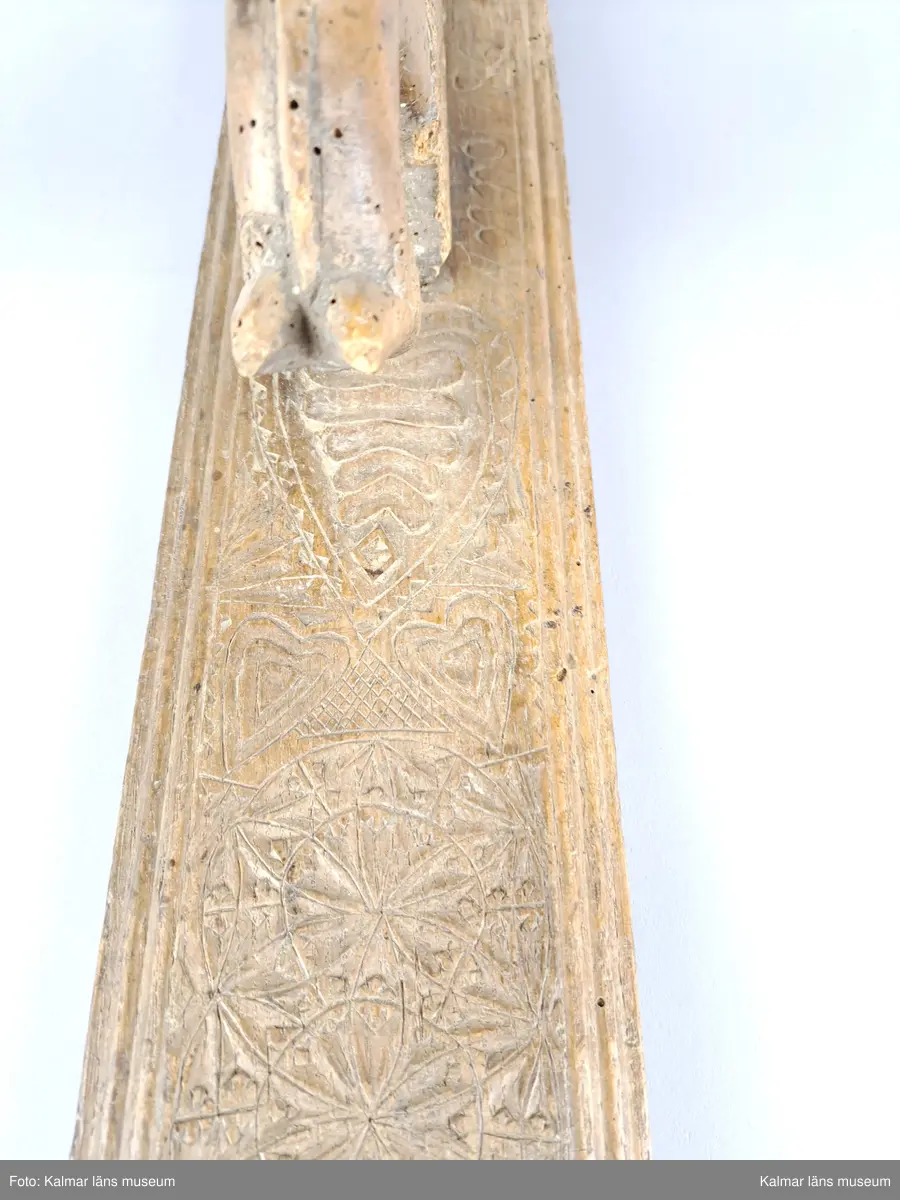 KLM 8325. Mangelbräde. Tillverkat av bok. Platt med kälade kanter. Ytan rikt ornerad med karvsnitt, cirklar, blommor, hjärtan m.m. Snidat handtag i form av en häst, något skadat. Inskrift: Anno 1786.
