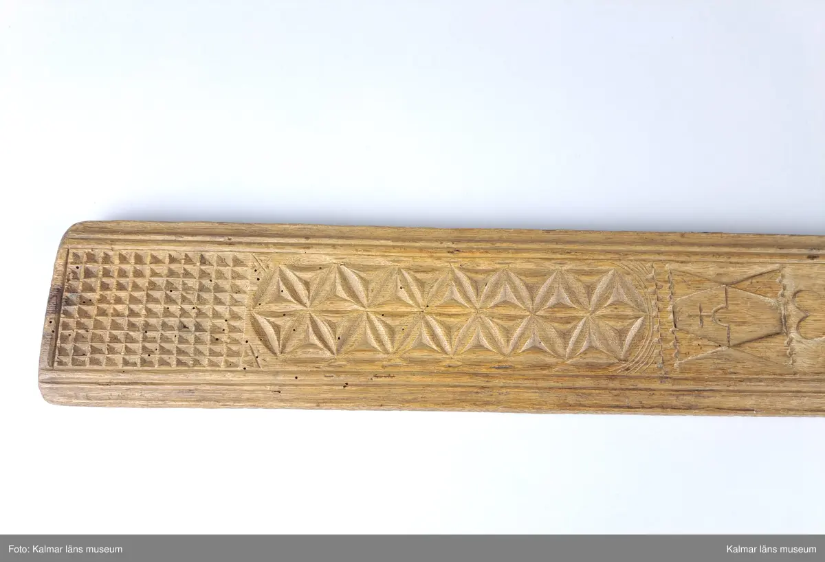 KLM 16532. Mangelbräde. Tillverkat av trä. Ytan med karvsnitt och plattskärningar, blommor, hjärtan, geometriska figurer. Snidat handtag i hästform. På ena sidan inskrift: S:P. C:P. d 16 juni 1800.