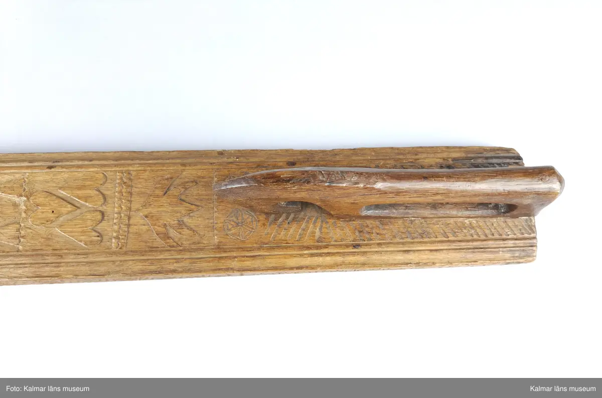 KLM 16532. Mangelbräde. Tillverkat av trä. Ytan med karvsnitt och plattskärningar, blommor, hjärtan, geometriska figurer. Snidat handtag i hästform. På ena sidan inskrift: S:P. C:P. d 16 juni 1800.