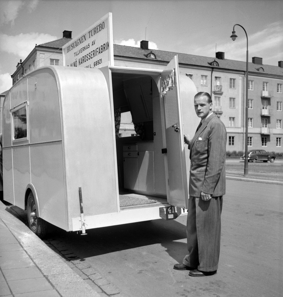 Representant från Alnö karosserifabrik i Sundsvall demonstrera företagets husvagnsmodell "Turebo" framför Östergötlands museum i Linköping. Foto 1949.