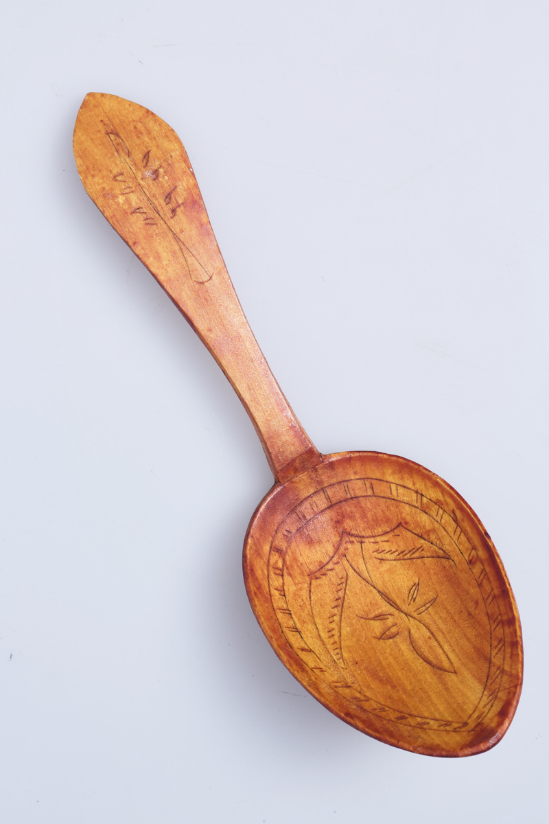 Totenskje dekorert med utskjæringer på begge sider av skjebladet og på skaftet.
