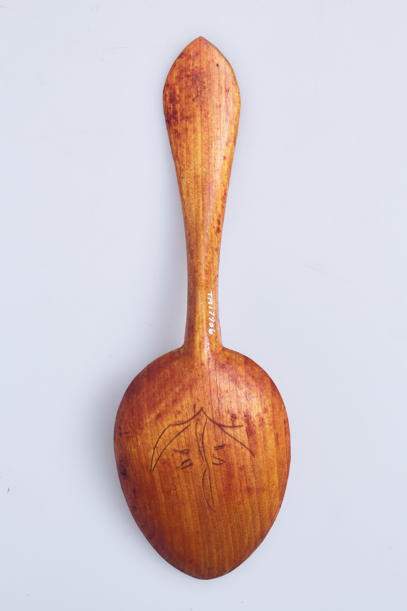 Totenskje dekorert med utskjæringer på begge sider av skjebladet og på skaftet.
