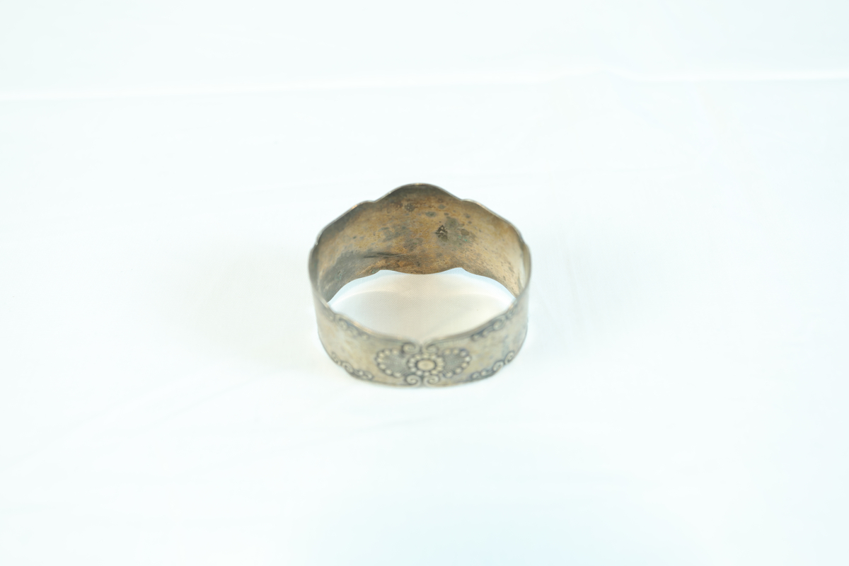 Lite og bredt armbånd i sølv eller tinn. Prydet med mønster og navnet "Klara" i løkkeskrift. 