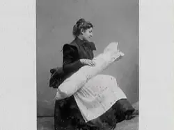 Kvinna med ett lindebarn. Eventuellt arrangerad bild. Troligen Agnes Pehrson med barn. Mor och barn. Familjebild.
