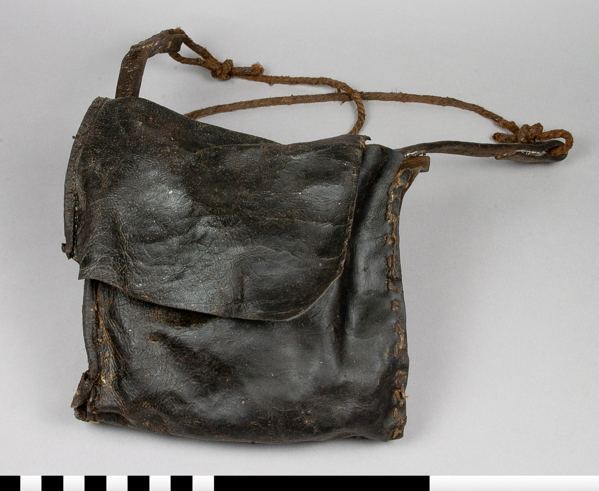 Väska i läder, med nitad axelrem av läder och rep av beckat lin. 

Funktion: Förvaring av redskap i samband med gruvarbete. I detta sammanhang tre kilar av järn SKAFÖR.0016457, SKAFÖR.0016458, SKAFÖR.001659.