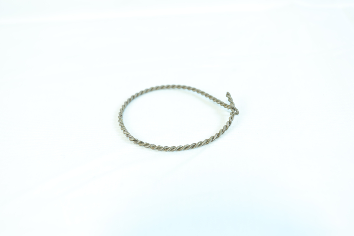 Armbånd i metallisk materialet. Tråen er dobbel, ved at to tråder er tvinnet sammen. Festet med en liten løkke. 