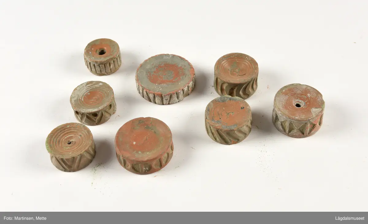 Samling av 11 ulike trykkblokker/stempel i keramikk, et målebånd og keramikkbollen de ble oppbevart i i Hansens verksted.