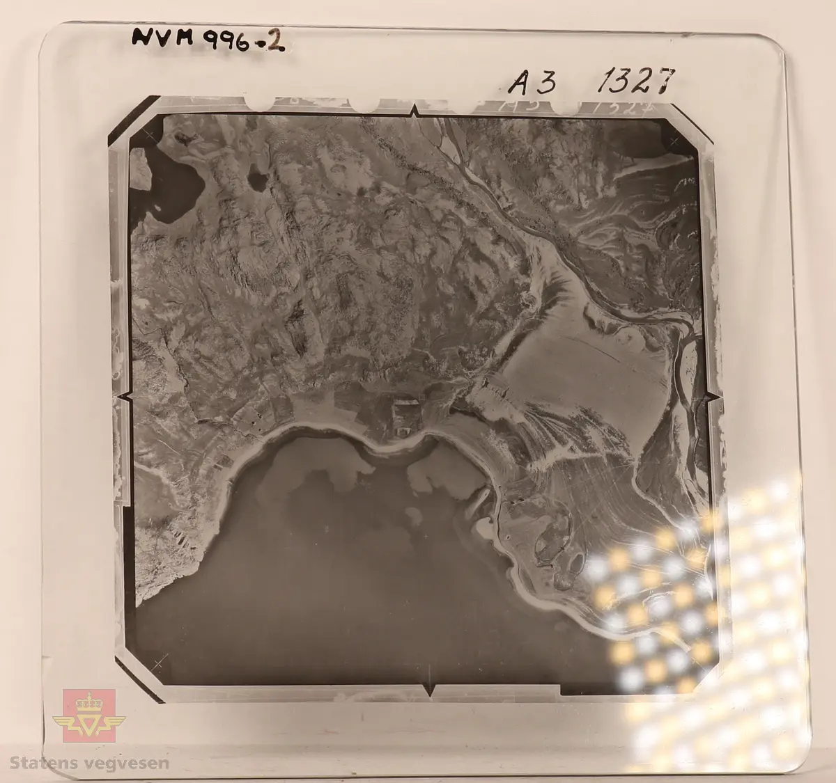 19 stk landskapsfoto på glassplate i svart/hvitt. Fotografiene er flyfoto i fugleperspektiv, langt over selve landskapet. Ligger samlet i en eske i egne små beskyttelses poser av papir. Merket med lapper mellom. 