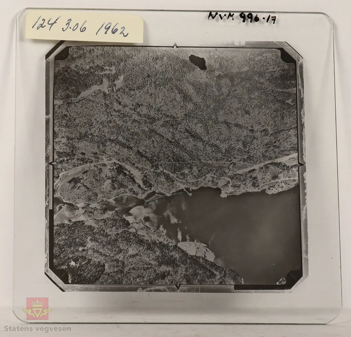 19 stk landskapsfoto på glassplate i svart/hvitt. Fotografiene er flyfoto i fugleperspektiv, langt over selve landskapet. Ligger samlet i en eske i egne små beskyttelses poser av papir. Merket med lapper mellom. 