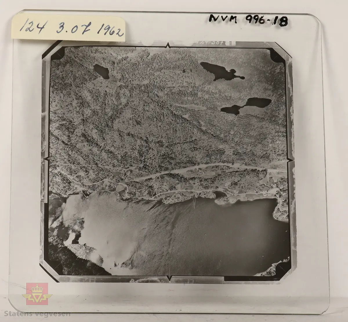 19 stk landskapsfoto på glassplate i svart/hvitt. Fotografiene er flyfoto i fugleperspektiv, langt over selve landskapet. Ligger samlet i en eske i egne små beskyttelses poser av papir. Merket med lapper mellom. 