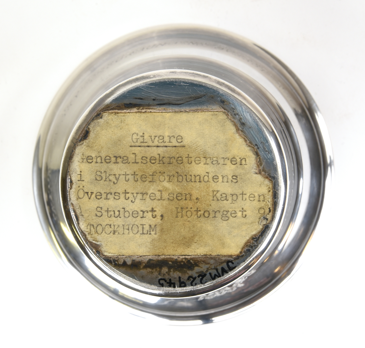 Bägare av silver. Konisk form med utvikt kant upptill. Graverad emblem och text framtill "RIKSHEMVÄRNSTÄVLINGEN 1959" och baktill "SKÄNKT AV SKYTTEFÖRBUNDENS ÖVERSTYRELSE".