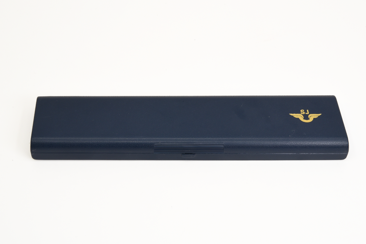 Armbandsur (:1) i blå förvaringsask (:2).

Runt armbandsurets inglasade urtavla löper en grå metallram. Bandet är tillverkat av svart skinn. Urtavlan är vit med svarta detaljer samt en röd sekundvisare. På urtavlan syns texten QUARTZ samt SJ:s firmamärke i svart. Längst ut på bandet sitter ett spänne i grå metall.
Förvaringsasken är av blå plast. På utsidan finns SJ:s firmamärke i "guldfärg". Askens insida är klädd med grå textil.