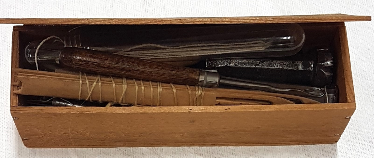 En samling broderiprover, bland annat pinnspets och näversöm. 
Proverna är av varierande storlekar, från ca 10 cm till 50 cm. 
En trälåda innehållande verktyg för nålbindning.