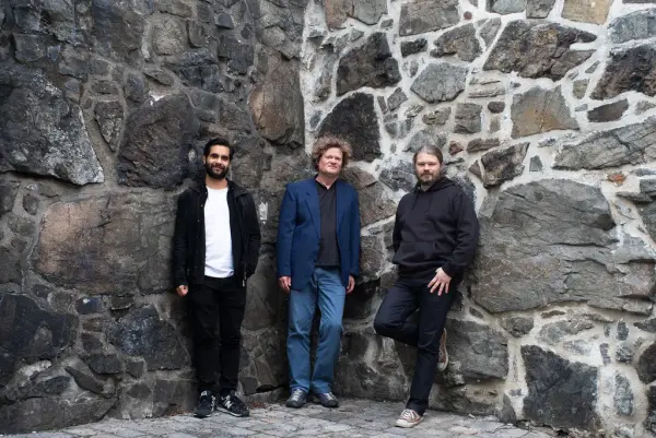 Trioen Haakon Ellingsen, Jacob Holthe Thorsen og Gaute Storsve står foran en steinmur.