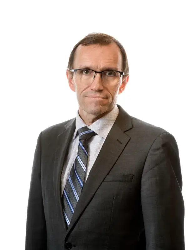 Portrett av utenriksminister Espen Barth Eide i dress og slips, stående mot hvit bakgrunn.