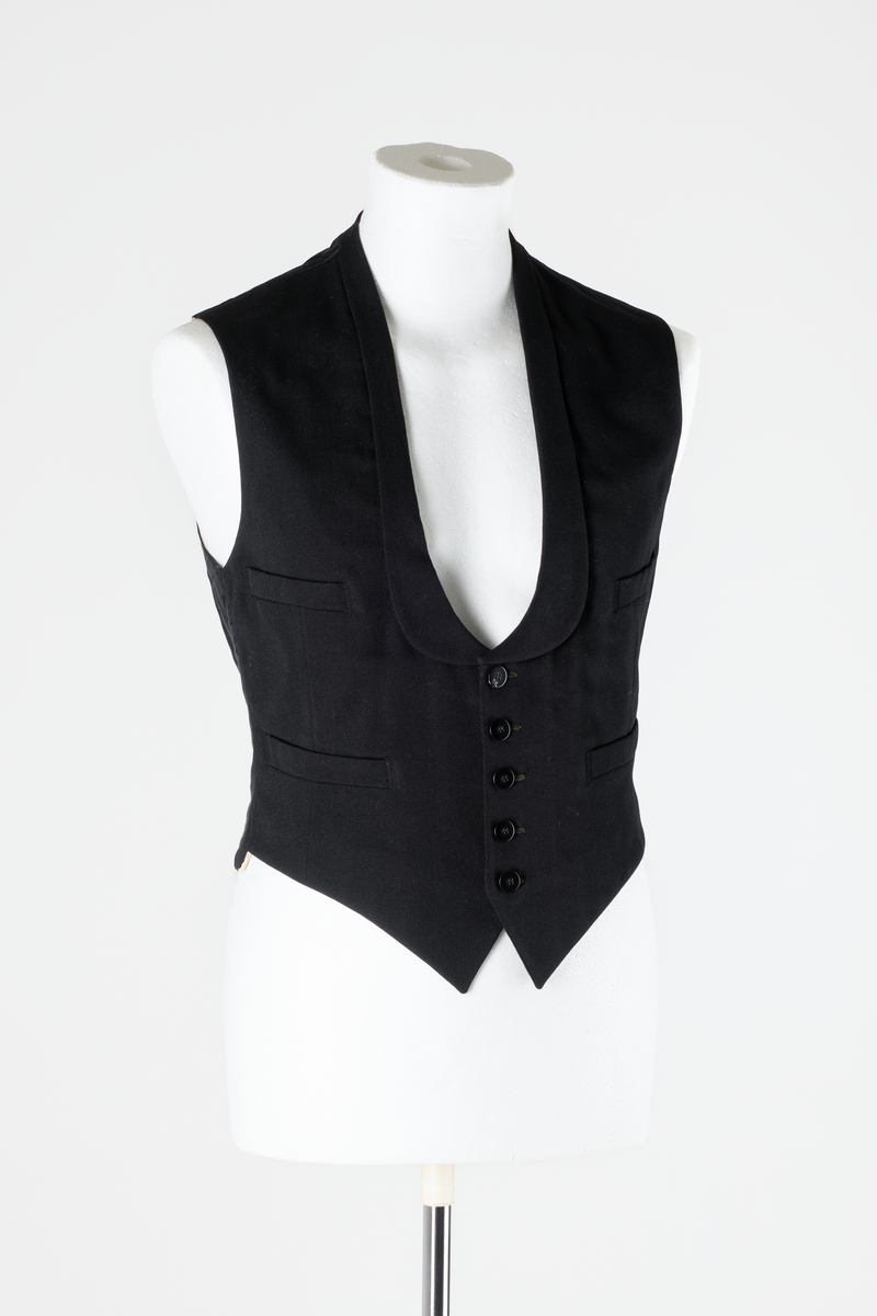 Sjakett av vanlig type. Sort jakke, enkeltspent og med store krageslag. Forstykket har buede kanter og er kortere enn ryggstykket. Ryggstykket har splitt midt bak med to knapper over splitten. Sort fôr i ryggen, hvitt fôr med sort striper inne i ermene.