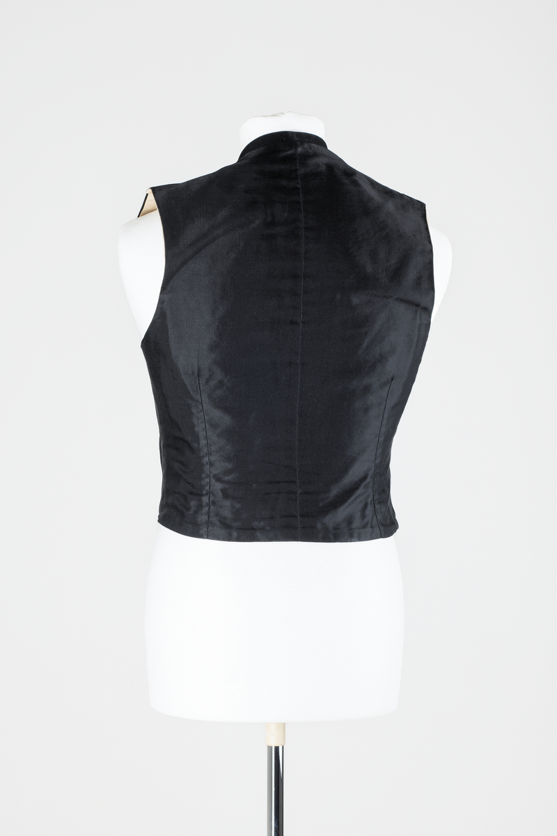 Sjakett av vanlig type. Sort jakke, enkeltspent og med store krageslag. Forstykket har buede kanter og er kortere enn ryggstykket. Ryggstykket har splitt midt bak med to knapper over splitten. Sort fôr i ryggen, hvitt fôr med sort striper inne i ermene.